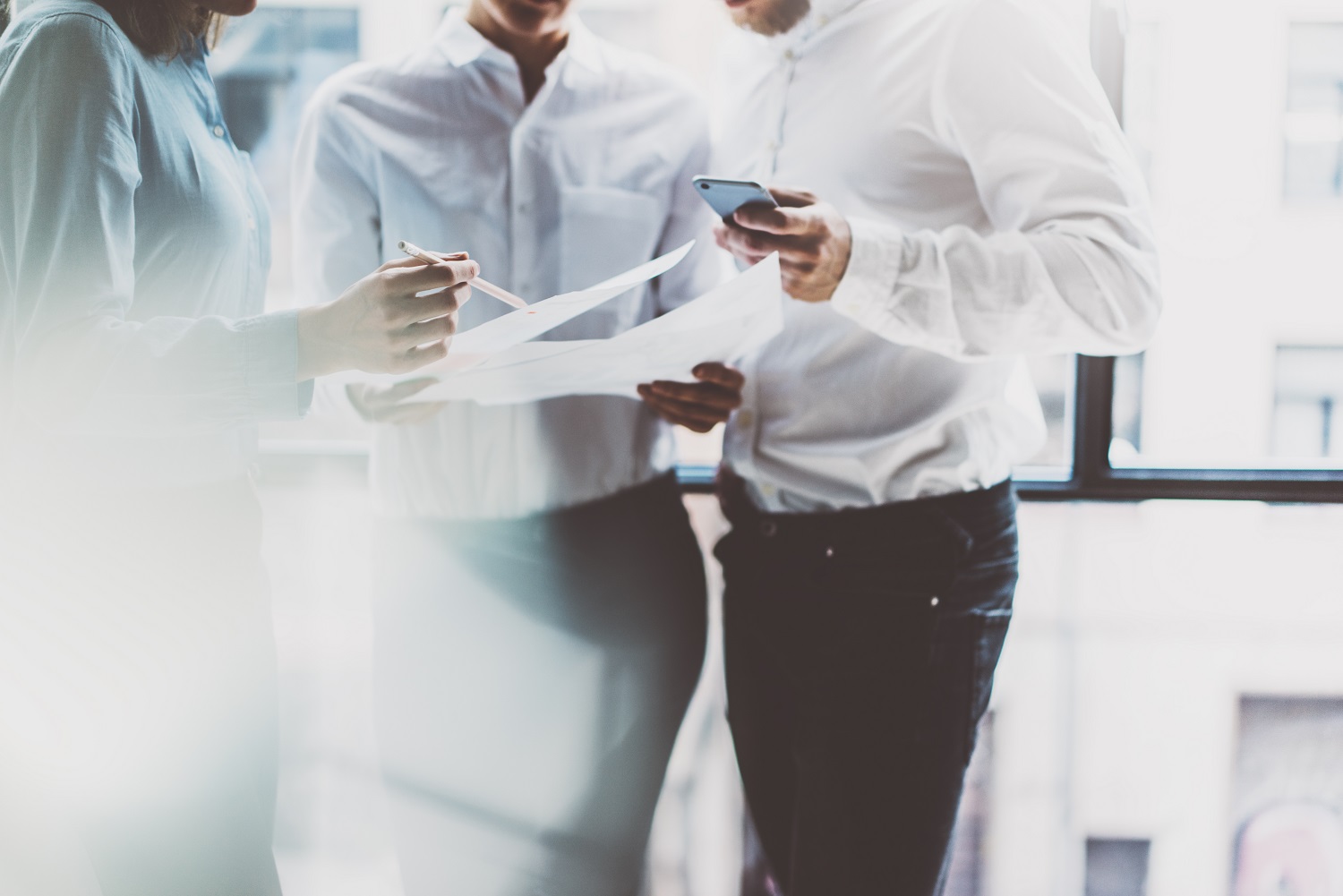 3 standing people discussing business