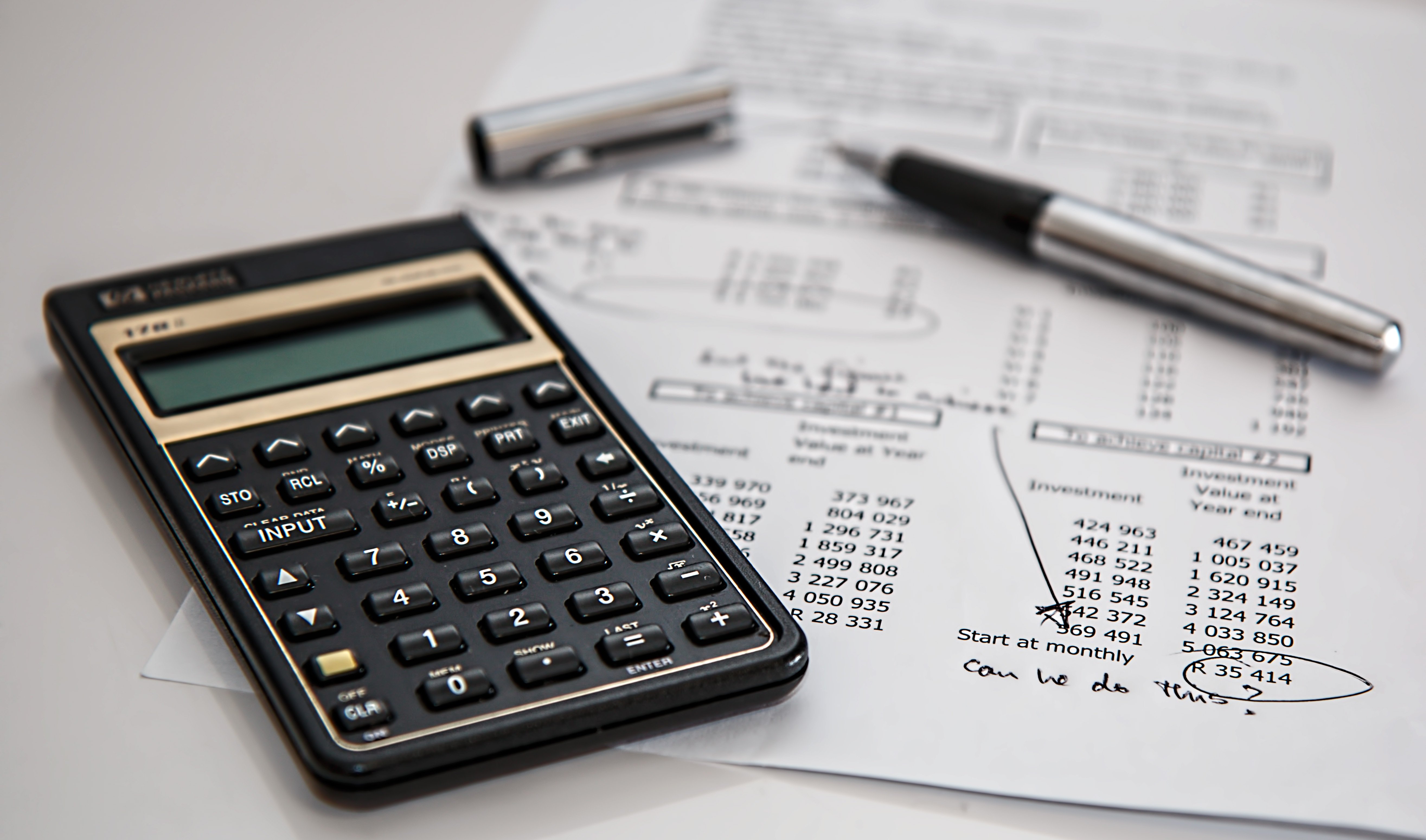 close up of calculator and pen and paper on table