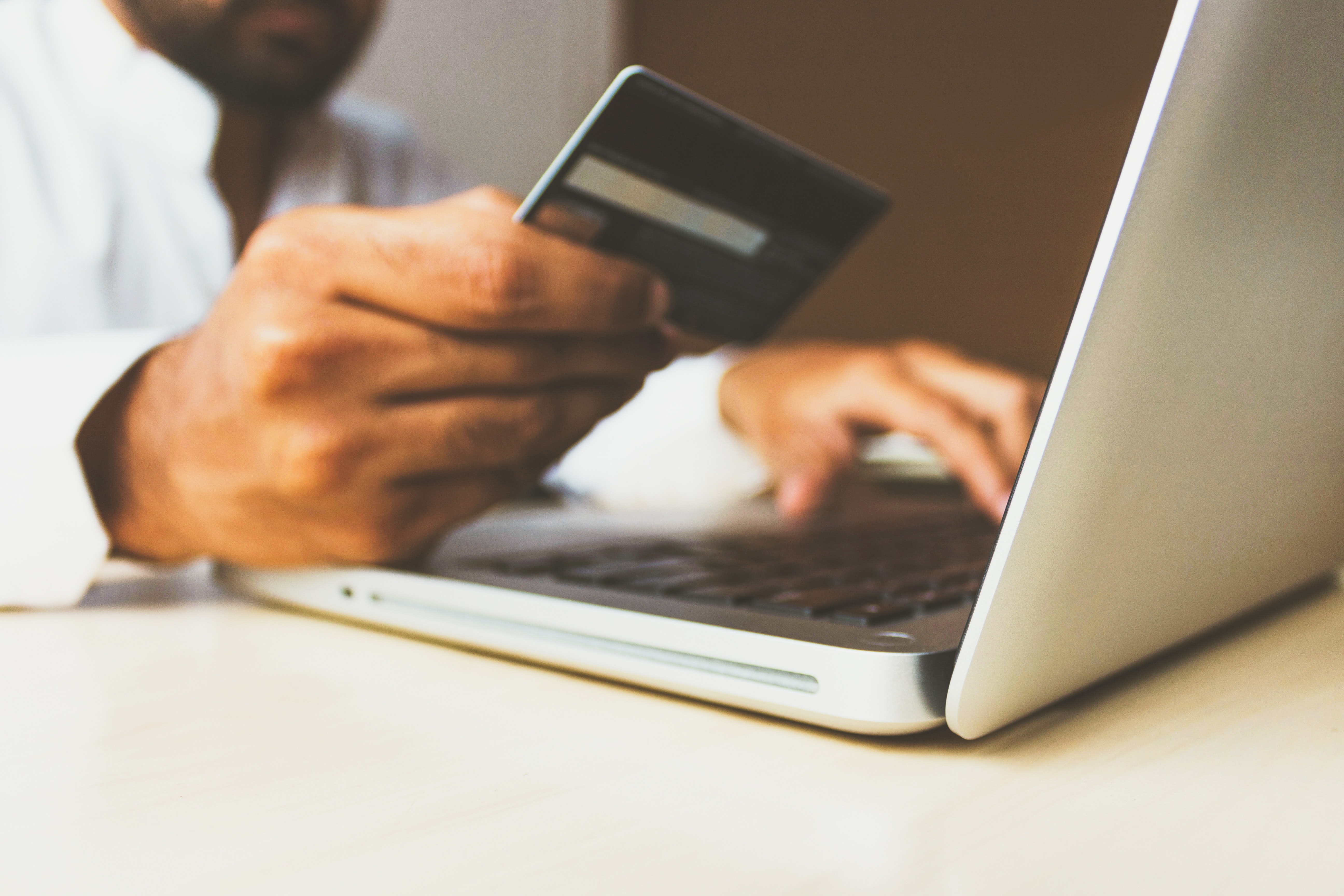 man holding credit card in front of laptop