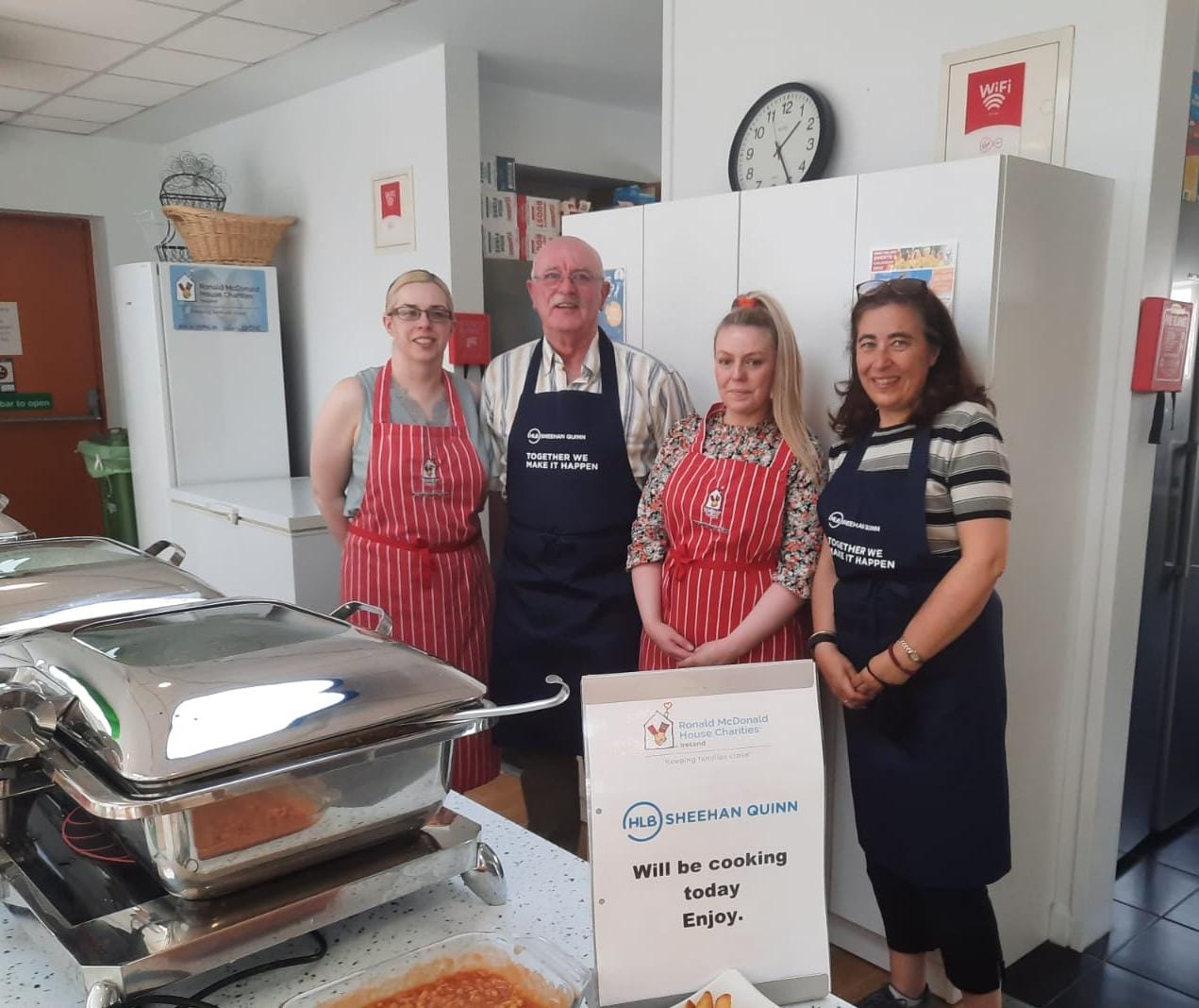 4 people with aprons in kitchen