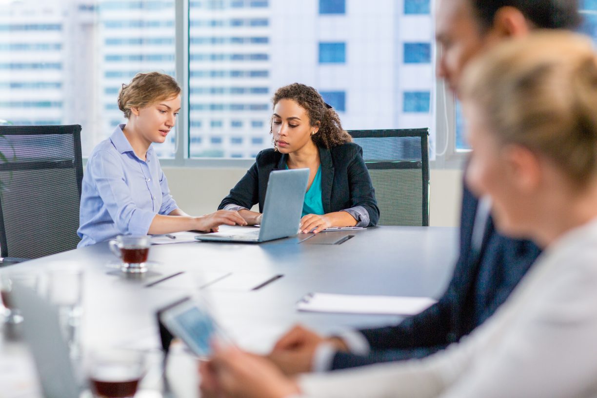 an outsourced finance team sits in a meeting room in a modern office, reviewing data on laptops